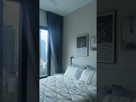 Bedroom features: king-size bed, upholstered headboard, bedding with geometric pattern, floor-to-ceiling windows, curtains in grey, framed artwork on walls, decorative wall art, light-colored walls, wooden flooring, city view from window; style: modern; view: city.