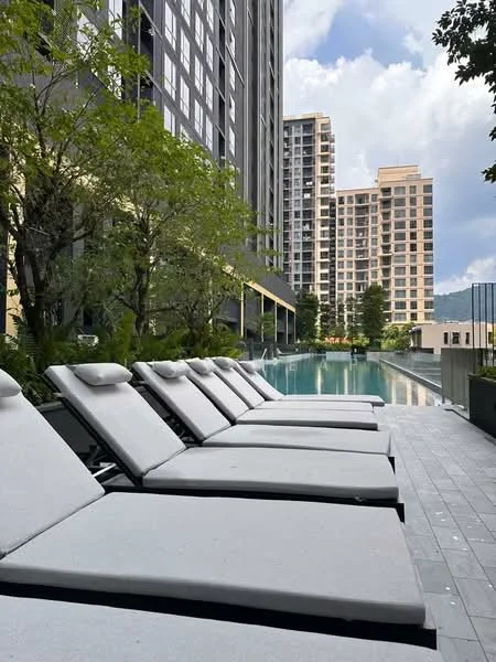 Exterior type: high-rise condominium; features: infinity pool, pool deck with loungers, tall residential buildings in background, manicured landscaping, trees surrounding pool area, modern architectural design, outdoor seating area, grey tiled flooring around pool; style: modern.