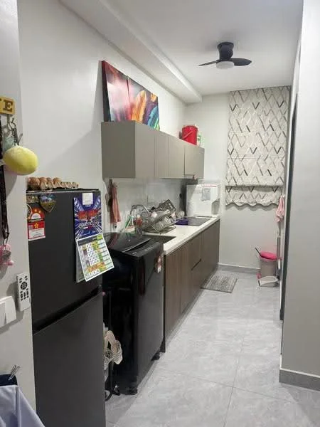 Kitchen features: grey tiled flooring, white painted walls, wood cabinetry, black refrigerator, black countertop, stainless-steel sink, chrome pull-down faucet, wall-mounted ceiling fan, window with sheer curtains, colorful artwork on wall, dish rack, kitchen utensils on wall; style: modern.