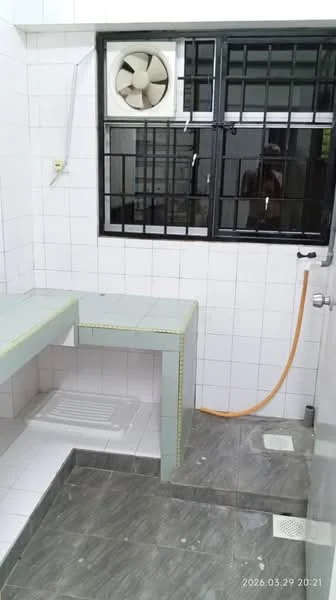 Bathroom features: white tiled walls, grey ceramic tile flooring, built-in countertop with sink, exhaust fan, window with security bars, shower area, drainage floor grate, orange hose, showerhead, wall-mounted faucet.