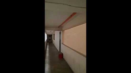 Room features: concrete flooring, white painted walls, exposed ceiling, lighting fixtures, narrow hallway, doorways leading to rooms.