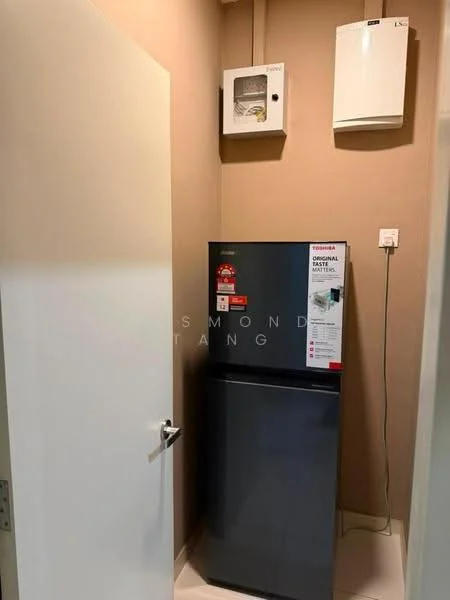 Room features: grey fridge, white walls, light-colored flooring, electrical panel, wall-mounted air conditioning unit, door with handle.