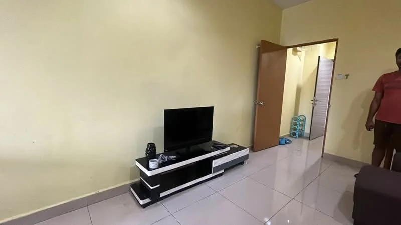 Living features: light yellow painted walls, glossy white tile flooring, black and white TV console, flat-screen TV, remote control, doorway leading to another room, door with handle, visible floor mat, blue storage rack in background.