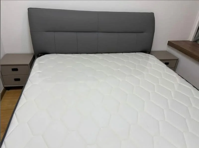 Bedroom features: queen-size bed, upholstered headboard in grey, two bedside tables with drawers, wooden flooring, white painted walls, window with natural light; style: modern.