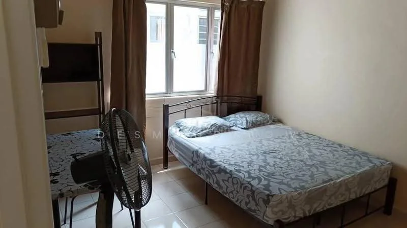 Bedroom features: queen-size bed with patterned bedding, wooden bed frame, two pillows, floor-to-ceiling window, brown curtains, wall-mounted TV, metal shelving unit, table with patterned tablecloth, standing fan, cream painted walls, glossy tile flooring.