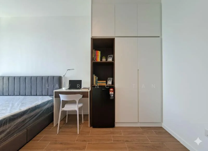 Bedroom features: queen-size bed with grey upholstered headboard, wooden flooring, built-in wardrobe with white finish, study desk with lamp, white plastic chair, small fridge, bookshelf with books, neutral painted walls, window with natural light; style: modern.