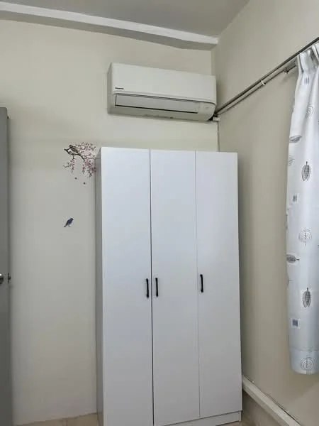 Room features: white wardrobe with three doors, wall-mounted split AC, light-colored walls, curtains with a pattern, flooring with light color, decorative wall art with floral design, metal door handle on wardrobe; style: modern.