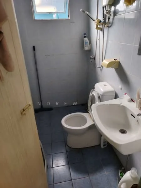 Bathroom features: white ceramic toilet, single-sink vanity with white cabinet, chrome basin mixer faucet, mirror above sink, shower head with adjustable height, blue ceramic tile flooring, light blue wall tiles, window for natural light, toilet paper holder, soap dispenser, cleaning broom, towel rack.