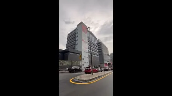 Exterior type: mid-rise condominium; features: glass curtain wall, grey painted facade, recessed balconies, multiple storeys, street-level parking, urban context with surrounding buildings; style: modern.
