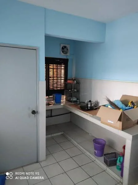 Kitchen features: blue painted walls, white tiled backsplash, grey countertop, single-bowl stainless-steel sink, chrome faucet, built-in cabinetry, window with wooden blinds, floor tiles, air conditioning unit, storage boxes, cleaning supplies.