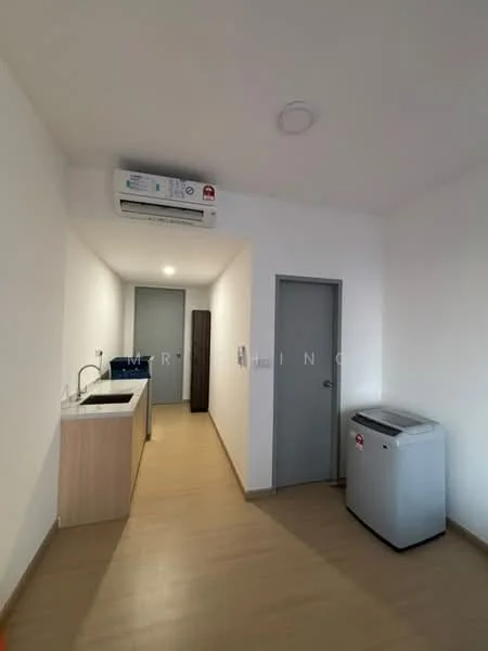 Room features: white painted walls, light wood laminate flooring, wall-mounted split AC, recessed ceiling lights, kitchenette with sink, countertop with storage cabinets, grey refrigerator, door to hallway; style: modern.