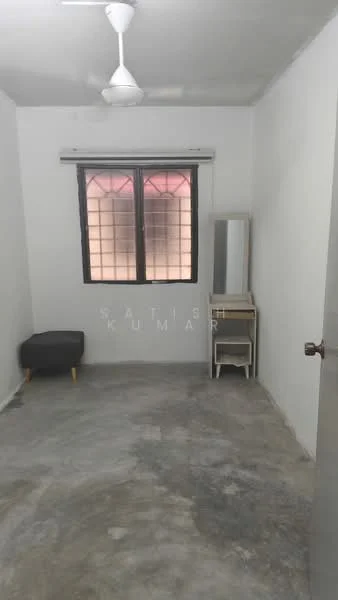 Room features: white painted walls, concrete flooring, single ceiling fan, window with grid pattern, mirror on a stand, small stool, wooden side table.