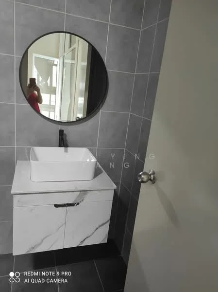 Bathroom features: grey tiled walls, black tiled flooring, round mirror, white countertop with marble pattern, single-bowl sink, black faucet, cabinet with white finish, door with silver handle; style: modern.
