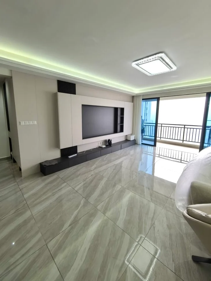 Living features: large flat-screen TV mounted on wall, built-in entertainment unit with storage, light grey wall with recessed lighting, floor-to-ceiling windows, sliding glass door leading to balcony, marble tile flooring, false ceiling with LED strip lighting, neutral color palette, balcony view; style: modern; view: city.