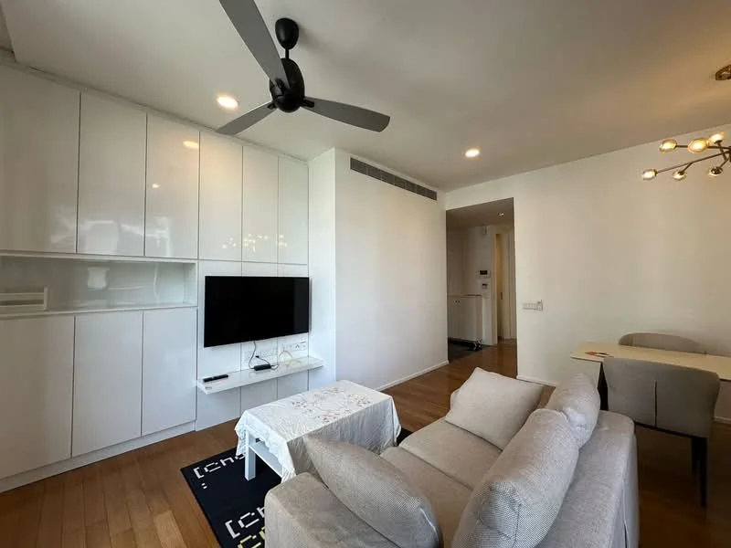 Living features: light grey fabric sofa, white coffee table, black area rug with geometric pattern, wall-mounted TV, white built-in cabinetry, ceiling fan with 5 blades, recessed lighting, wooden flooring, open layout to dining area, large windows with natural light; style: modern. Room features: white walls, wooden flooring, doorway leading to hallway, light fixtures.