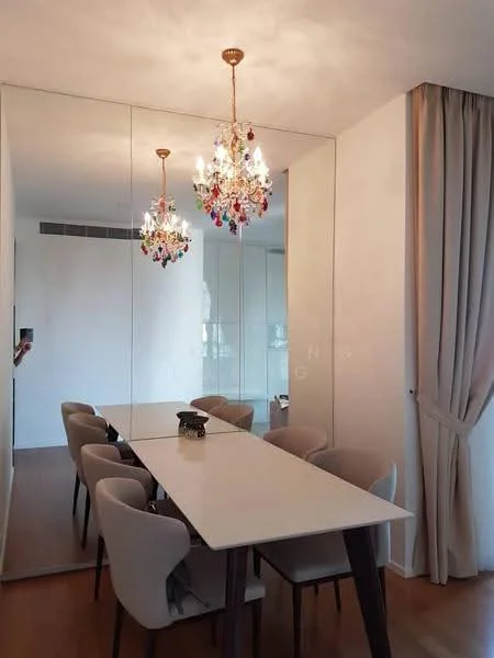 Dining features: long rectangular dining table, upholstered dining chairs, chandelier with colorful accents, mirrored wall, wooden flooring, curtains, wall-mounted light switch, neutral wall color; style: modern.