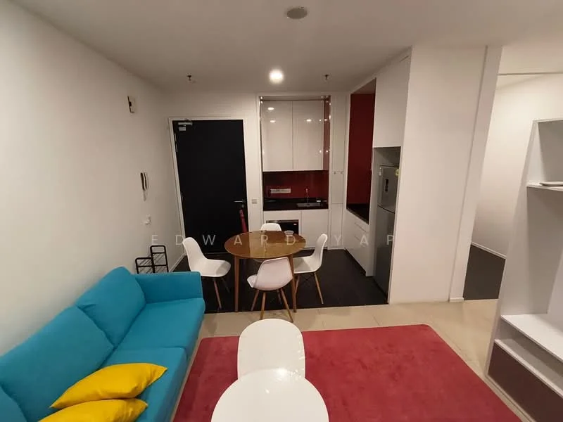 Living features: turquoise fabric sofa, yellow throw pillows, white coffee table, red area rug, dining table with white chairs, wall-mounted TV, white painted walls, tile flooring, recessed downlights; style: modern. Kitchen features: white cabinetry, black countertop, built-in oven, stainless-steel fridge, red accent wall, sink, ceramic tile backsplash; style: modern.