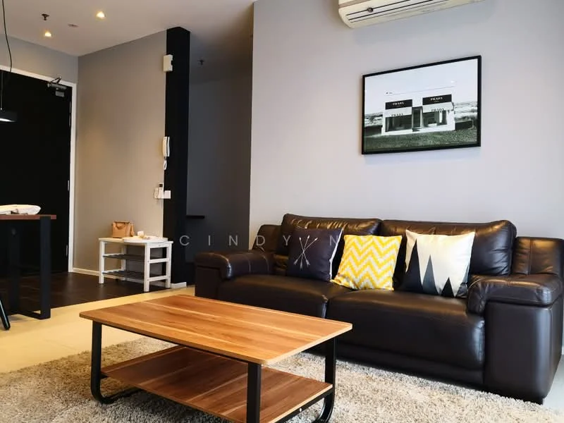 Living features: 3-seater leather sofa in dark brown, wood coffee table, area rug with neutral color, framed artwork on wall, grey painted walls, ceiling-mounted air conditioning unit, wall-mounted light fixture, decorative cushions with geometric patterns, open shelving unit, flooring with tiles, visible electrical outlets; style: modern.