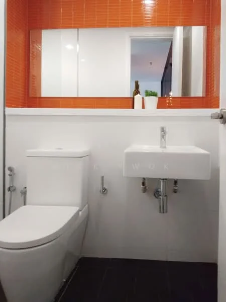 Bathroom features: white tiled walls, orange accent wall with square tiles, black tile flooring, single-sink vanity with wall-mounted faucet, one-piece toilet, mirror above sink, decorative plant on vanity, chrome plumbing fixtures; style: modern.