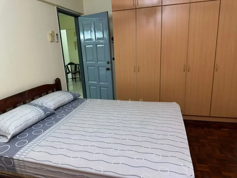 Bedroom features: queen-size bed with patterned bedding, wooden bed frame, built-in wardrobe with sliding doors, light blue painted walls, parquet wood flooring, single bedside lamp, window with no visible treatment, door leading to hallway.