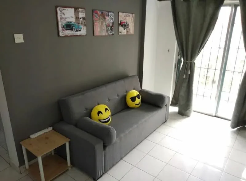 Living features: grey fabric sofa, two decorative smiley face cushions, light-colored side table, white tiled flooring, grey painted walls, floor-to-ceiling sliding glass door, curtains in dark green, framed artwork on wall; style: modern.