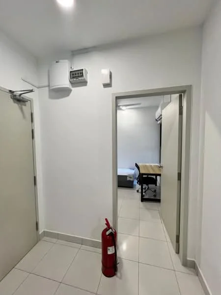 Room features: white painted walls, tile flooring, fire extinguisher, ceiling-mounted air conditioning unit, light fixture, door with handle, door frame, open doorway leading to another room.