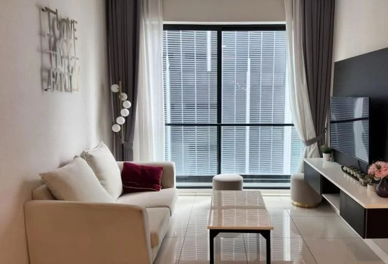 Living features: 3-seater fabric sofa in white, decorative cushions in burgundy, coffee table with wooden top, TV console with storage, wall-mounted TV, floor-to-ceiling windows, sheer curtains, grey drapes, ceramic tile flooring, decorative wall art, potted plant, light fixture with multiple bulbs; style: modern; view: city.