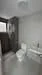 Bathroom features: white ceramic toilet, single-sink vanity with white cabinet, chrome basin mixer faucet, framed mirror, walk-in shower with glass enclosure, grey tile flooring, grey wall tiles, recessed downlights, exhaust fan; style: modern.