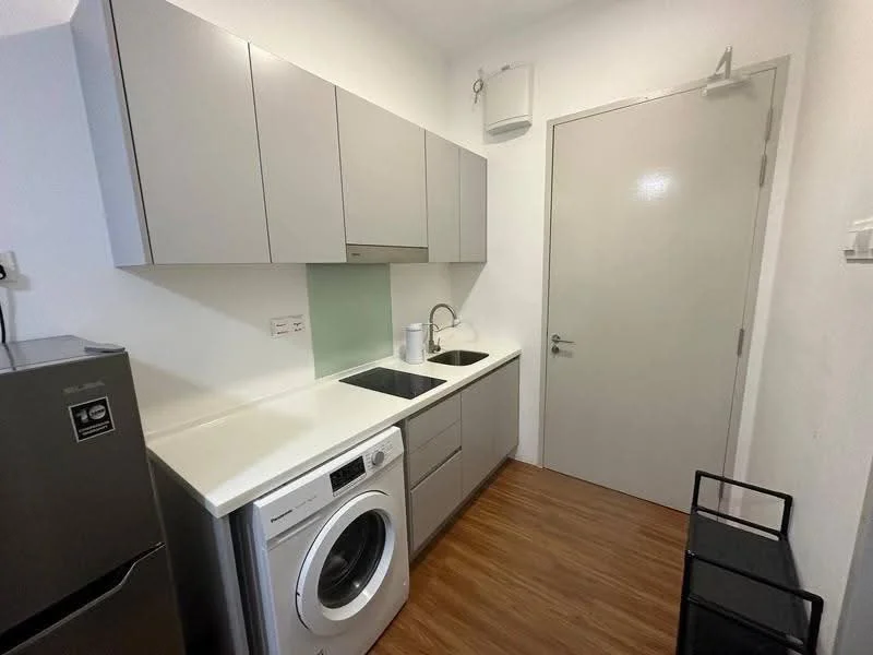 Kitchen features: grey flat-panel cabinets, white countertop, single-bowl stainless-steel sink, chrome pull-down faucet, built-in washing machine, stainless-steel fridge, light wood laminate flooring, green glass backsplash, wall-mounted air conditioning unit, door with handle; style: modern.