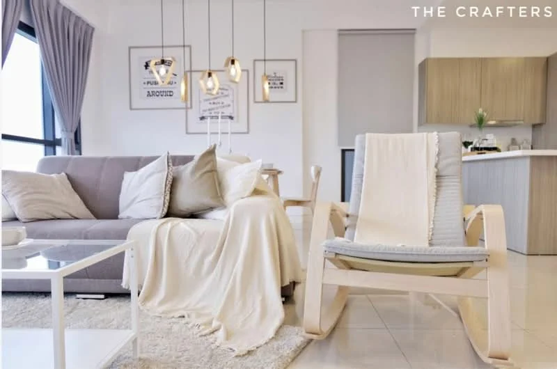 Living features: 3-seater fabric sofa in light grey, beige throw blanket on sofa, wooden rocking chair with cushion, white coffee table, pendant lighting with multiple bulbs, large windows with sheer curtains, light-coloured tiled flooring, framed artwork on walls, decorative plants, neutral colour palette; style: modern; view: city.