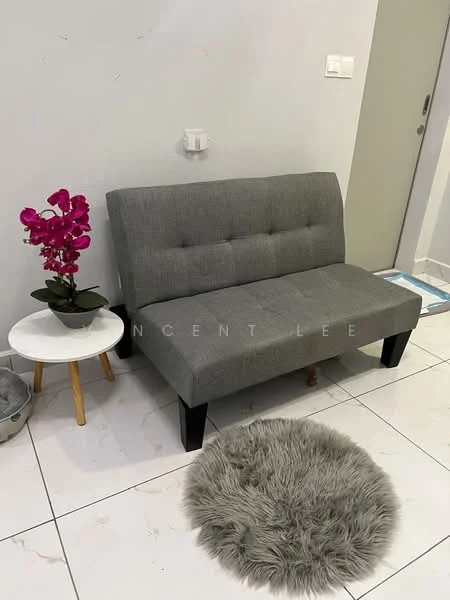 Room features: grey fabric loveseat, white round side table, wooden legs on side table, purple orchid plant in pot, fluffy grey area rug, white tiled flooring, light grey painted walls, wall-mounted electrical outlet; style: modern.
