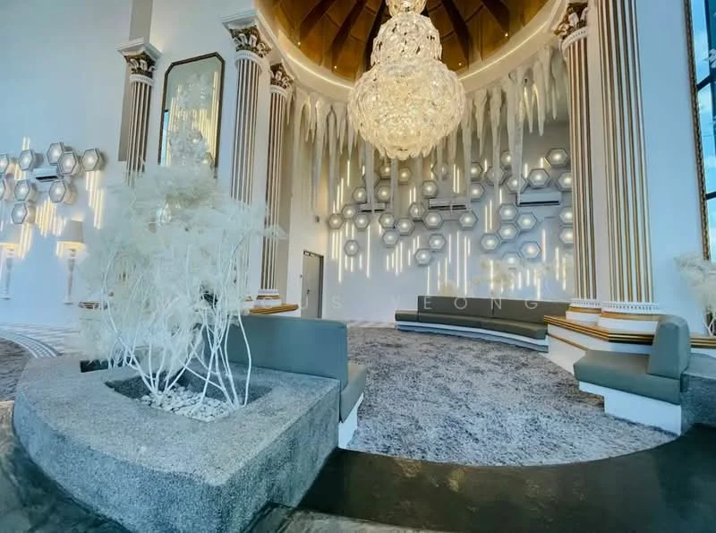 Room features: chandelier with multiple tiers, high ceiling with decorative beams, white walls with decorative moulding, grey upholstered seating, textured area rug, decorative wall panels with circular designs, stone planter with white branches, large windows allowing natural light; style: luxury; view: garden.
