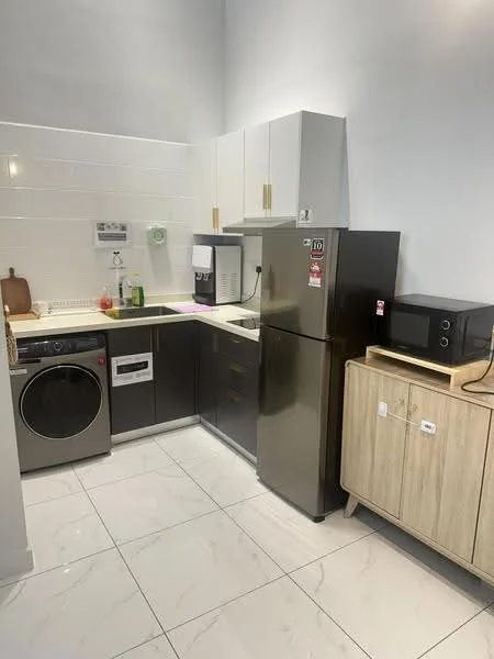 Kitchen features: white upper cabinets with gold handles, dark lower cabinets, black refrigerator, built-in washing machine, microwave, stainless-steel sink, countertop with cutting board, white tiled backsplash, white marble tile flooring, wall-mounted kitchen appliances, kitchen towel hanging, decorative items on countertop; style: modern.