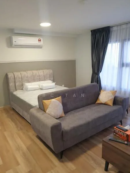 Bedroom features: queen-size bed with upholstered headboard, grey fabric sofa with decorative cushions, wooden flooring, wall-mounted split AC, floor-to-ceiling window with sheer curtains, grey accent wall, nightstand with books, decorative throw pillows; style: modern.