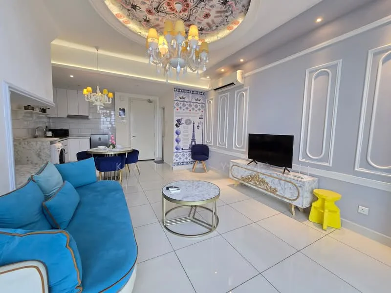 Living features: blue fabric sofa with gold trim, round marble coffee table, wall-mounted TV, chandelier with yellow shades, recessed LED downlights, white tiled flooring, decorative wall with blue and white tiles, feature ceiling with floral design, glass side table, yellow stool, dining table for four, white cabinetry in kitchen area; style: modern.