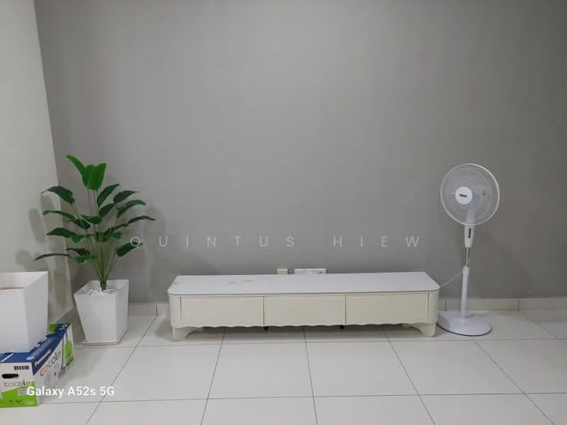Room features: light grey painted walls, white tiled flooring, white TV console, floor-standing fan, indoor plant in white pot, cardboard boxes, power outlet on wall; style: minimalist.