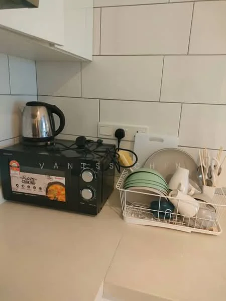 Kitchen features: black microwave oven, stainless-steel kettle, white dish rack, assorted plates in green and grey, cutlery holder with utensils, white tiled backsplash, white cabinetry, countertop; style: modern.