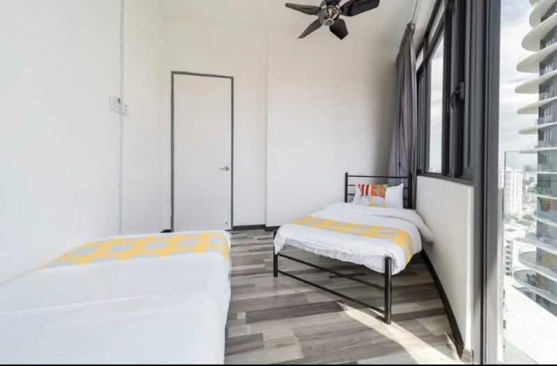 Bedroom features: two beds, black metal bed frame, white bedding, yellow accent throw on bed, wood-look laminate flooring, floor-to-ceiling windows, grey curtains, ceiling fan, white painted walls, door to hallway; style: modern; view: city.