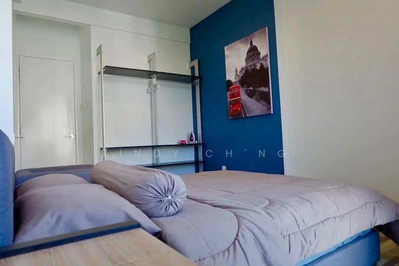 Bedroom features: queen-size bed with grey bedding, decorative bolster pillow, blue accent wall, white painted walls, built-in wardrobe with sliding doors, wooden bedside table, framed artwork on wall, flooring not visible; style: modern.
