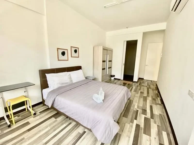 Bedroom features: queen-size bed with grey bedding, wooden headboard, two framed wall art pieces, built-in wardrobe with sliding doors, study desk with yellow legs, wooden flooring with mixed tones, air conditioning unit, white painted walls, ceiling light fixture; style: modern.