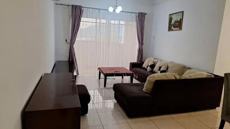 Living features: brown fabric L-shape sectional sofa, beige throw pillows, glass coffee table with red and black pattern, white painted walls, cream tiled flooring, curtains in light purple, ceiling light fixture with three bulbs, wooden console table against the wall, framed artwork on the wall; style: modern.