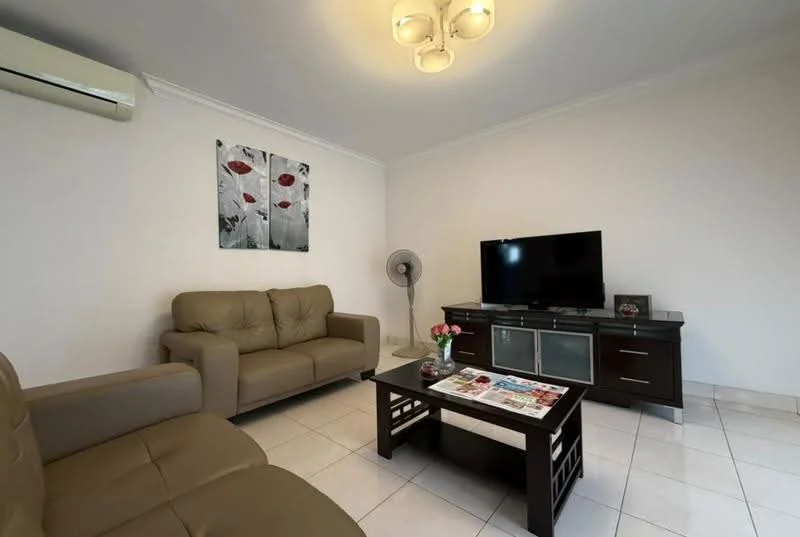 Living features: cream leather 3-seater sofa, cream leather 2-seater sofa, dark wood coffee table, flat-screen TV on dark wood console, decorative fan, wall-mounted air conditioning unit, framed artwork with floral design, white painted walls, tile flooring, ceiling light fixture with multiple bulbs; style: modern.