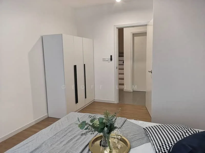 Bedroom features: white painted walls, laminate flooring, queen-size bed with grey bedding, built-in wardrobe with white doors and black handles, decorative tray with glass and greenery, doorway leading to hallway, light fixture on ceiling; style: modern.