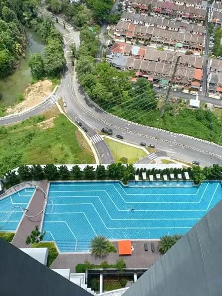 Exterior type: high-rise condominium; features: infinity pool, pool deck with loungers, landscaped garden area, surrounded by greenery, view of nearby residential area, road access, water feature, paved walkways; style: modern.