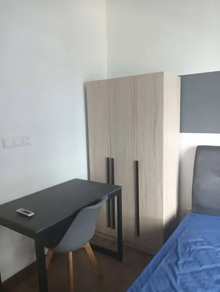 Bedroom features: wooden wardrobe with two doors, black desk with wooden legs, grey upholstered bed, blue bedspread, white painted walls, laminate flooring; style: modern.