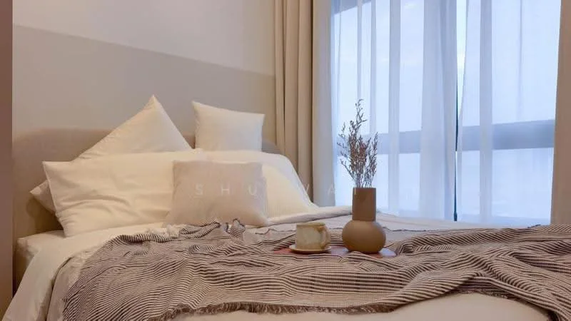 Bedroom features: queen-size bed with upholstered headboard, white bedding with decorative pillows, striped throw blanket, nightstand with decorative vase, window with sheer curtains, floor-to-ceiling window, light-colored walls, wooden flooring; style: modern; view: city.