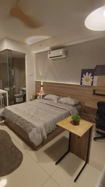 Bedroom features: queen-size bed with grey bedding, wooden headboard, nightstand with plant, desk with chair, wall-mounted air conditioning unit, recessed lighting, grey accent wall, white painted walls, tile flooring, area rug, floor-to-ceiling glass shower enclosure, toilet visible in bathroom area; style: modern.