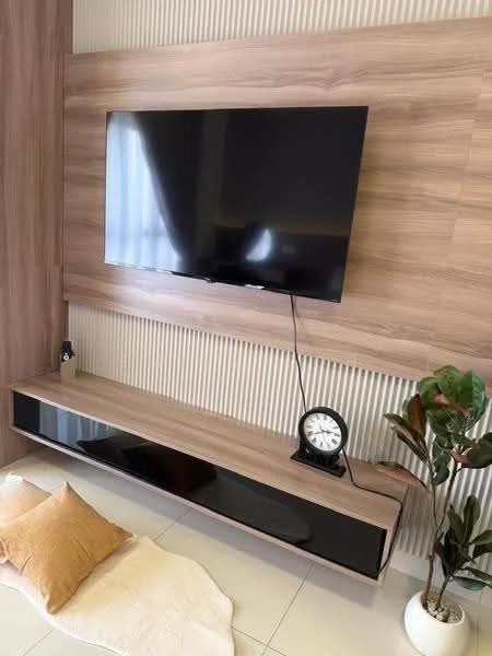 Living features: wall-mounted TV, wooden TV console with black accents, decorative clock, potted plant, neutral-colored area rug, cushion, textured wall paneling, light-colored tiled flooring; style: modern.