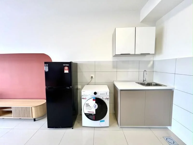 Kitchen features: black fridge, white washing machine, single-bowl stainless-steel sink, white countertop, light brown cabinetry, white tiled walls, grey tiled flooring, wooden cabinet with slatted design, pink accent wall; style: modern.