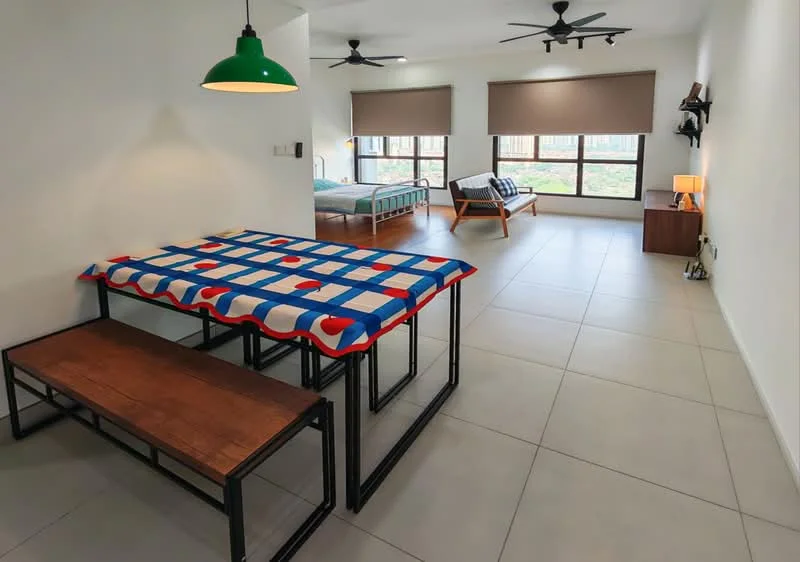 Living features: dining table with blue and red patterned tablecloth, wooden bench seating, 2 ceiling fans, large windows with roller blinds, tile flooring, neutral painted walls, wooden side table, bed in background, sofa bed in background; style: modern; view: garden.